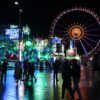 Wiesnbesucher gehen bei Regen über das Oktoberfest.