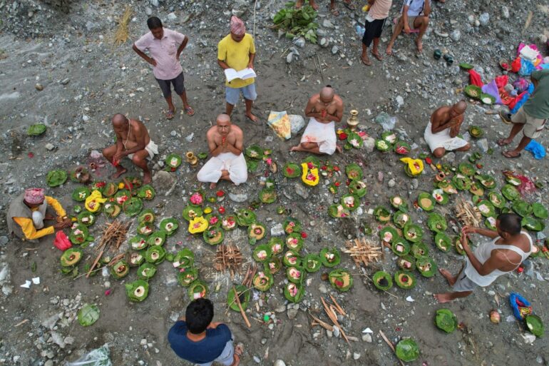 Menschen, deren Angehörige nach den Sturzfluten weiterhin vermisst werden, vollziehen am Ufer des angeschwollenen Trishuli-Flusses im nepalesischen Distrikt Nuwakot Rituale im Anschluss an symbolische Bestattungszeremonien.