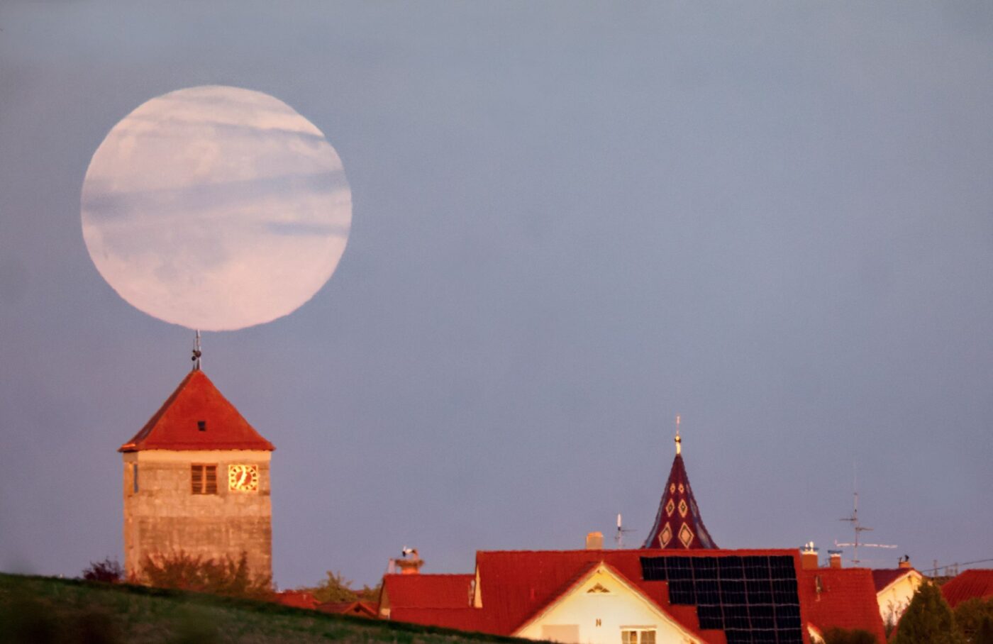 Während der Römerturm in Emerkingen von der Abendsonne angestrahlt wird, geht hinter ihm der Vollmond auf.