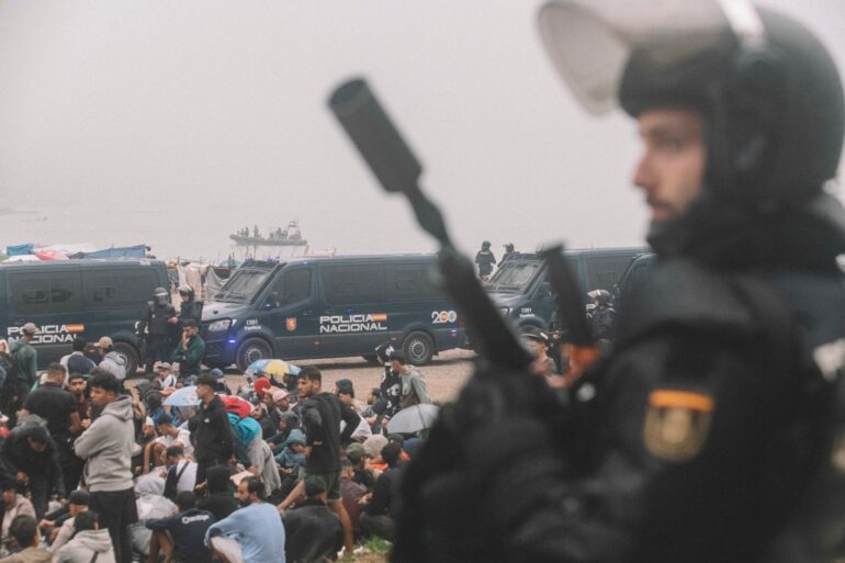Migranten wurden in Ceuta von starken spanischen Polizeikräften von einem Hüttenlager am Strand fortgebracht.