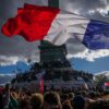 Eine Person hält bei einer Demonstration in Paris gegen unterfinanzierte Schulen eine französische Nationalfahne.