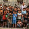 Menschen verfolgen ein Fußballspiel zwischen einer Mannschaft aus Gaza gegen eine Mannschaft aus Chan Yunis auf einem Gelände zwischen Zelten, in denen Binnenflüchtlinge untergebracht sind.