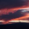 Vom Sonnenaufgang rötlich verfärbt zeigt sich der Himmel über dem Brocken in Sachsen-Anhalt.